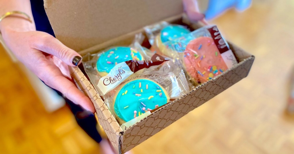 gifts under 10 - hands holding a cardboard box full of blue and pink sugar cookies