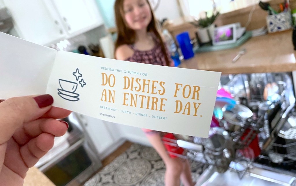 hand holding a mother's day coupon book in front of dishwasher