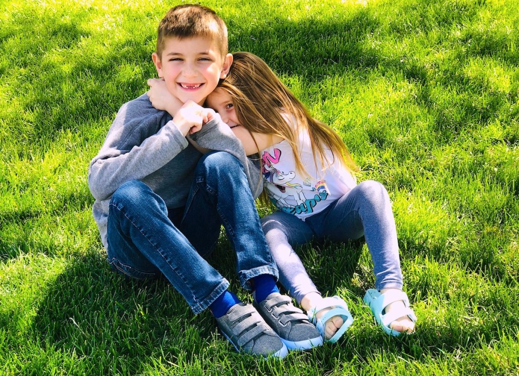 boy and girl hugging and smiling in green grass 