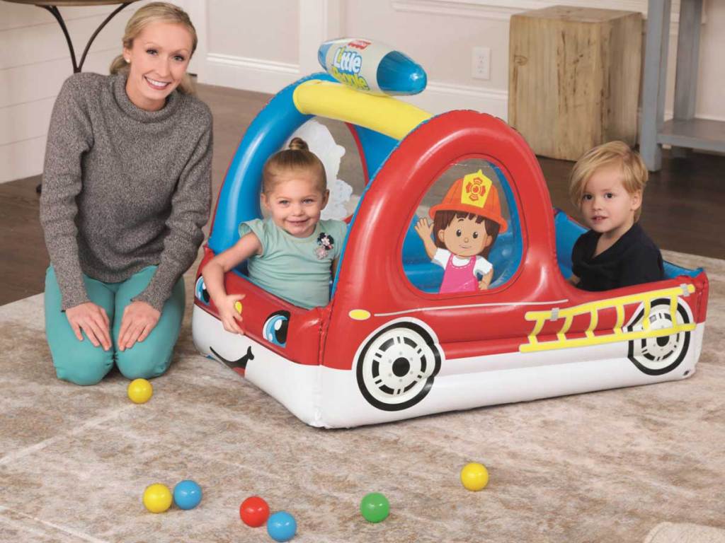 mom playing with young kids in a fire truck ball pit