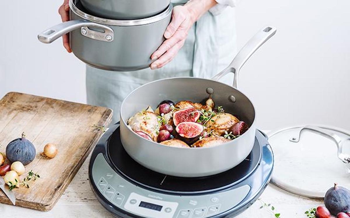 person holding pot next to saucepan with food sitting on burner