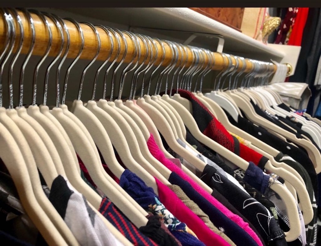 close up of beige velvet hangers with clothes hanging up in closet