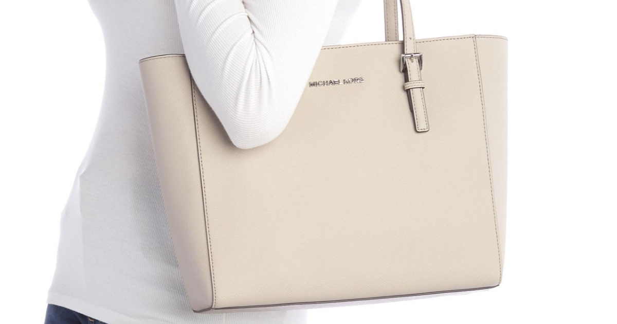 woman wearing white shirt carrying cement colored michael kors tote bag