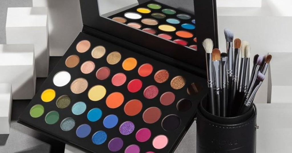 colorful eyeshadow palette with black cup holding makeup brushes