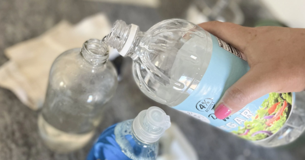 pouring white vinegar into bottle to make homemade vinegar cleaning solution