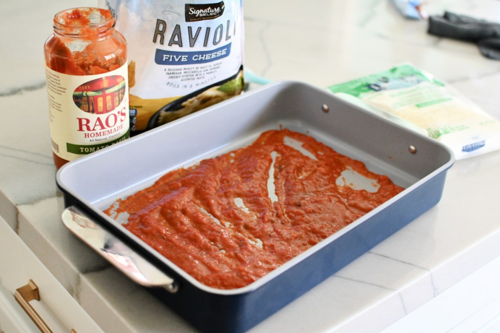 spreading Rao's marinara sauce on a baking dish