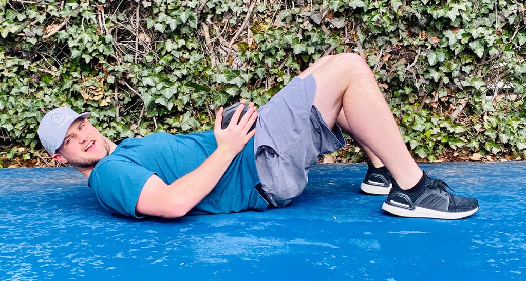 man laying on ground for glute bridge workout
