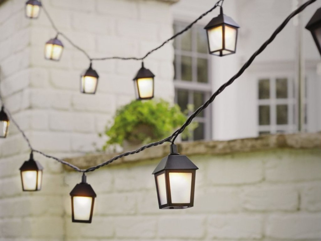 lantern lights hanging outdoors with white brick wall in background