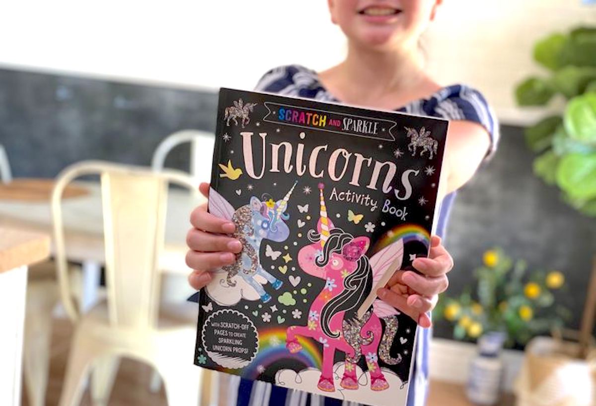 girl holding a unicorn activity book 