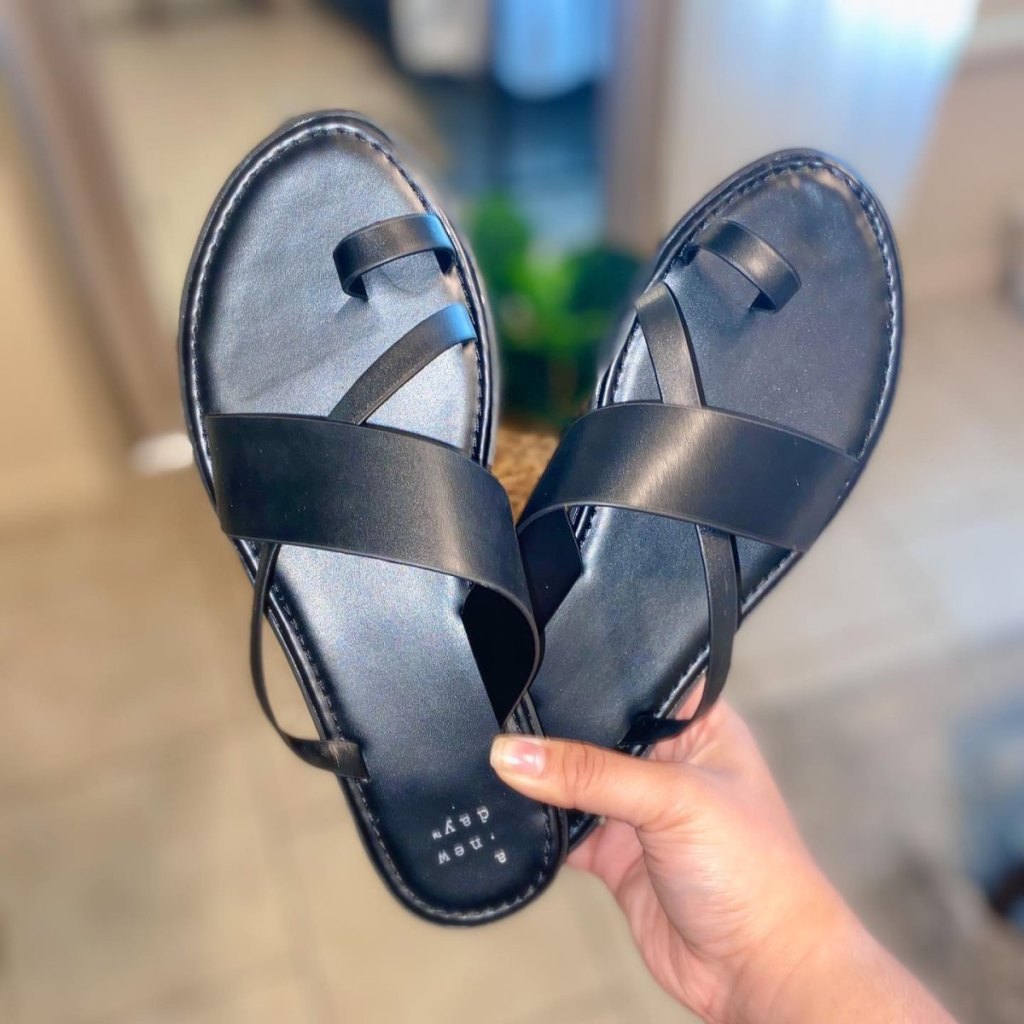 woman hand holding black pair of Women's Kallima Faux Leather Toe Ring Style Slide Sandals