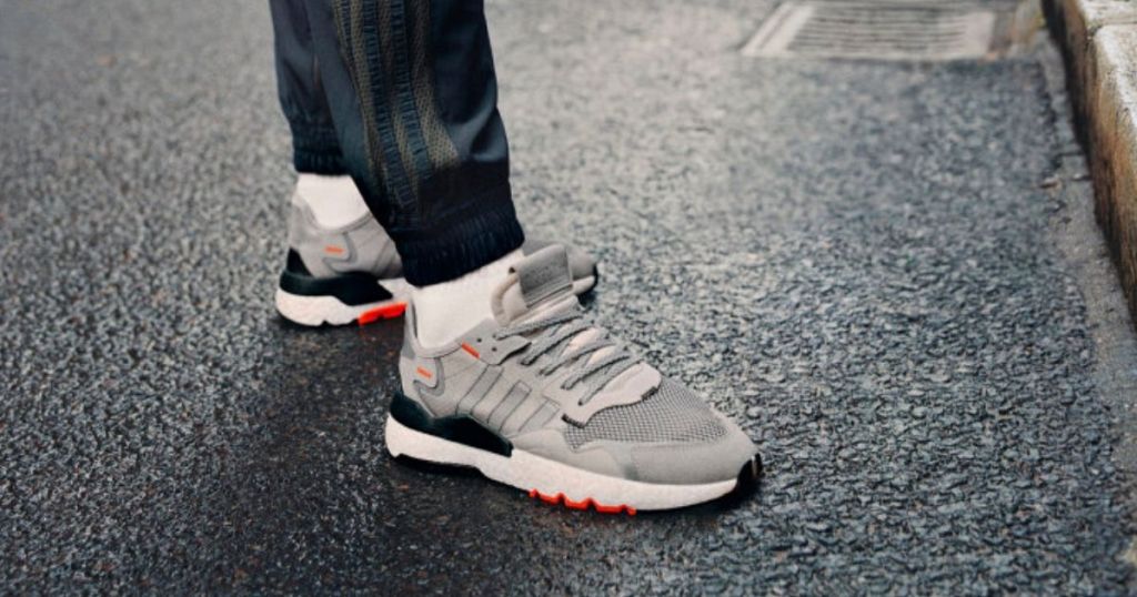 Adidas sneakers on mans feet standing on asphalt