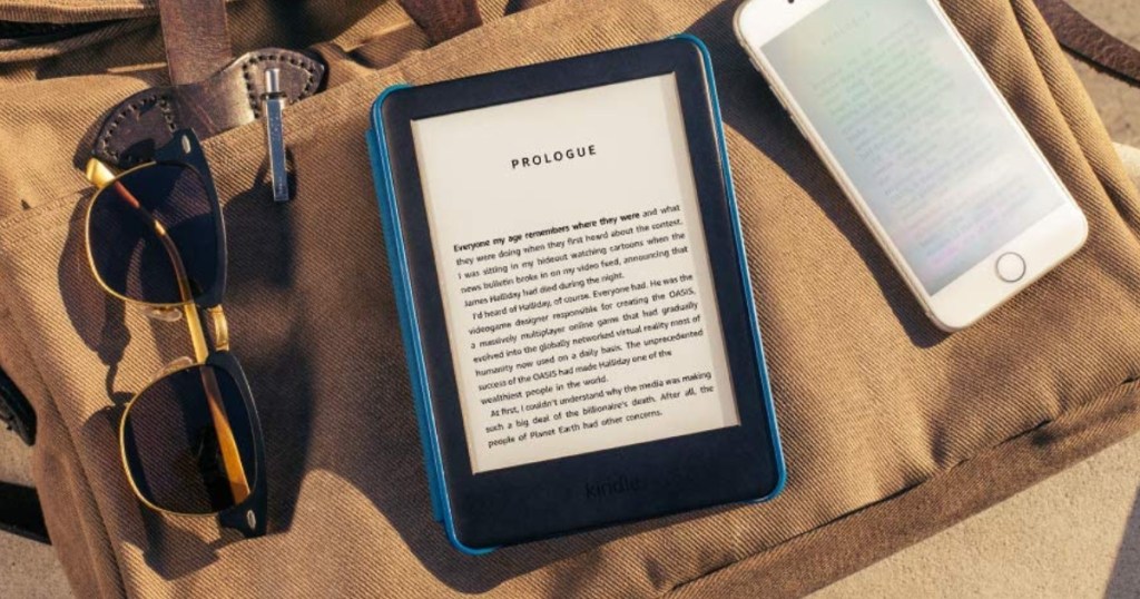 black e-reader, cell phone, and sunglasses, on tan canvas bag