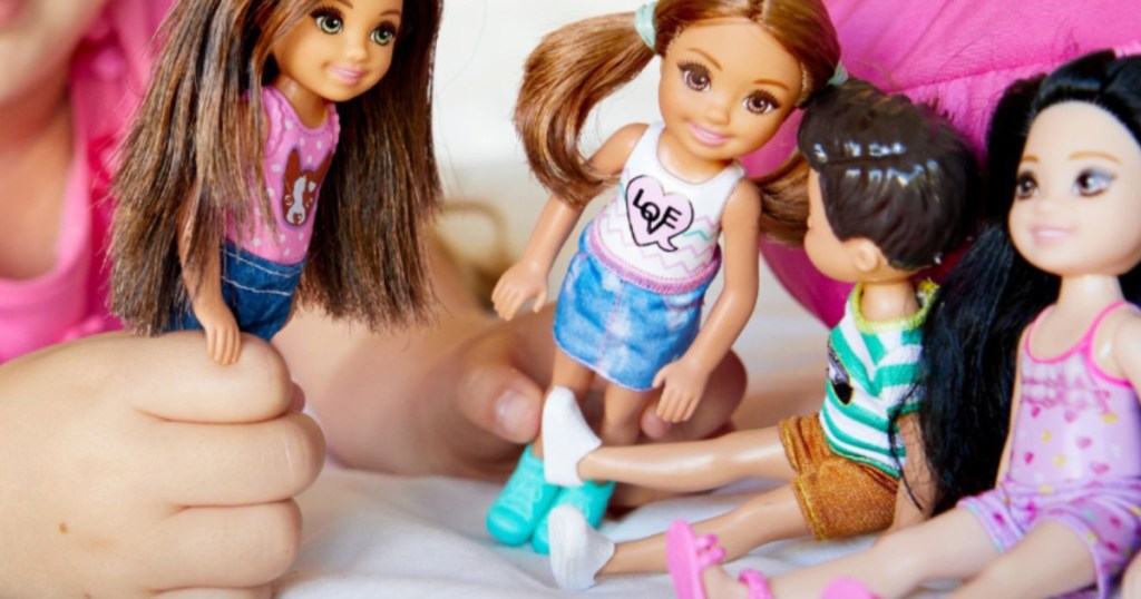 girl playing with four dolls on bed