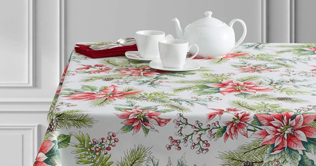 poinsetta tablecloth on table with white tea pot, cups, and plates on top