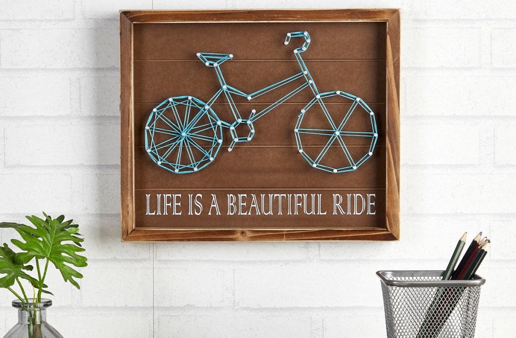 wall art made with string to shape a bike that reads life is a beautiful ride