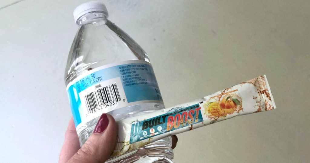 woman holding water bottle and drink packet