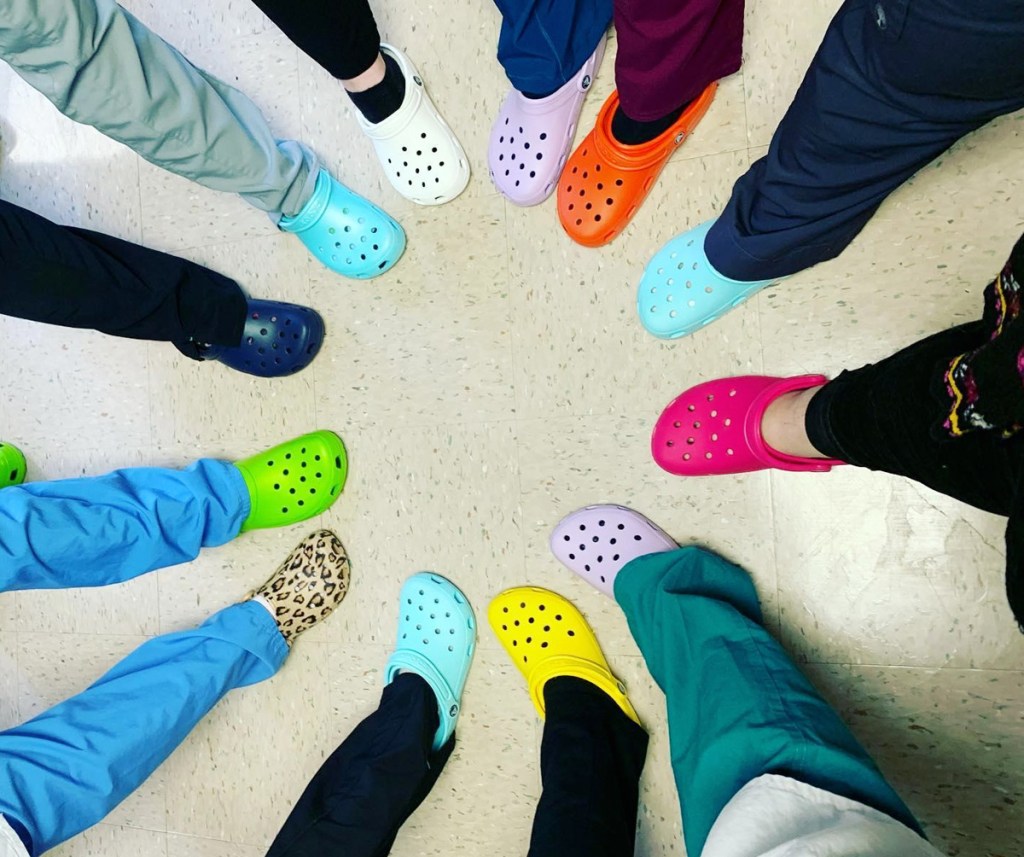 people wearing scrub pants and crocs sticking out their feet to form a circle