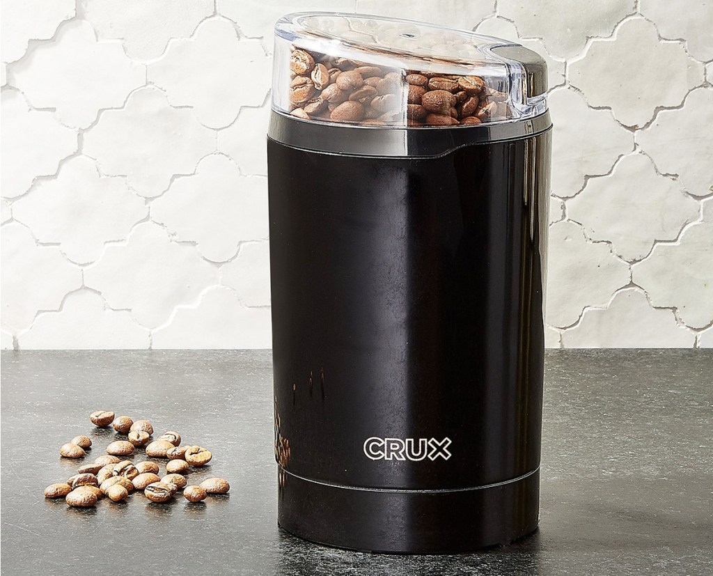 black coffee grinder with coffee beans inside sitting on kitchen counter