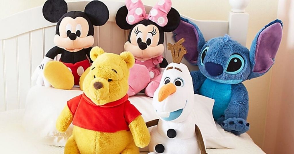 five medium stuffed disney plush animals on a bed