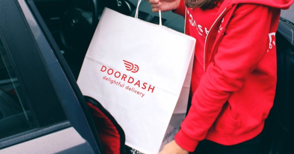 woman putting a white and red door dash bag into the front seat of her car