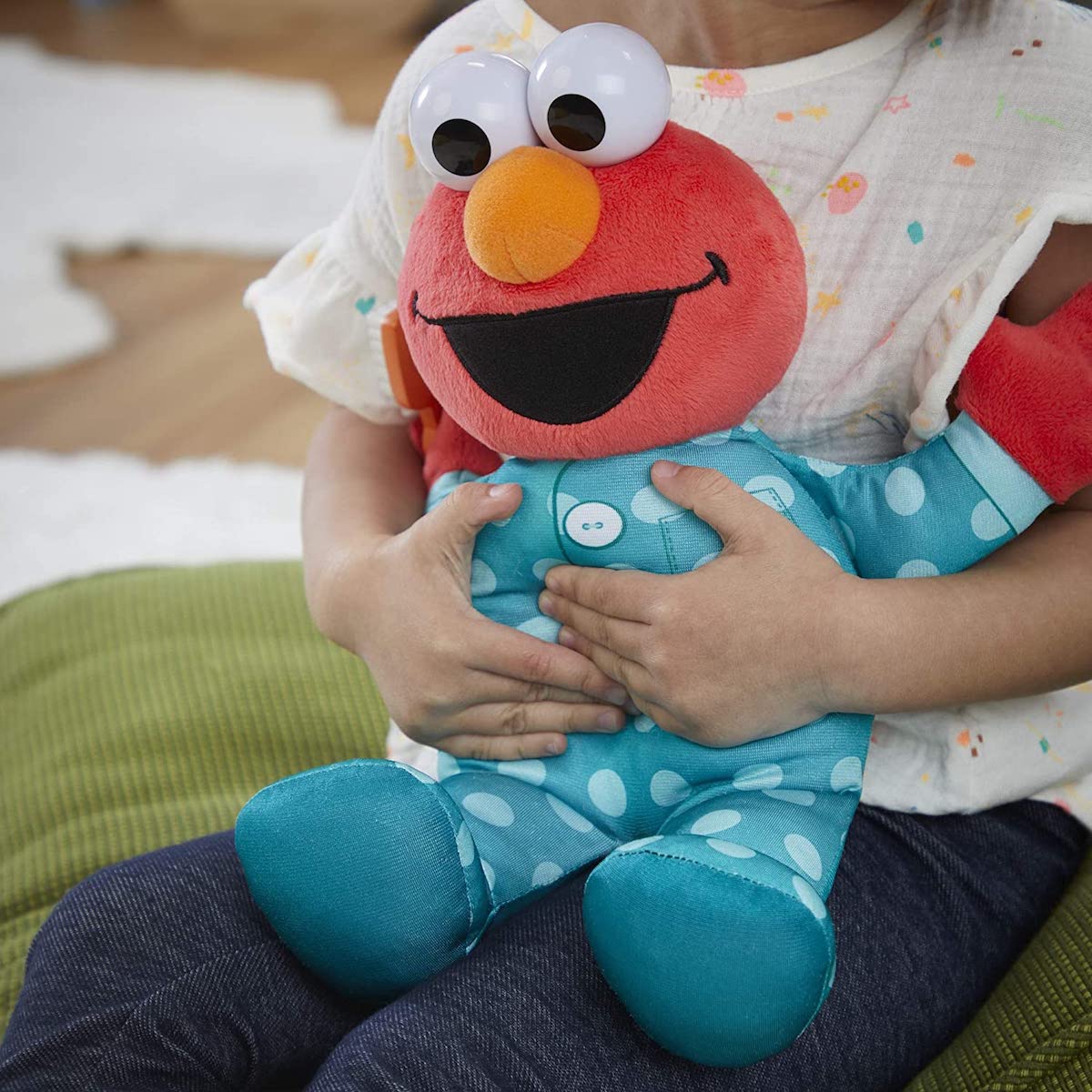 child holding an Elmo plush toy