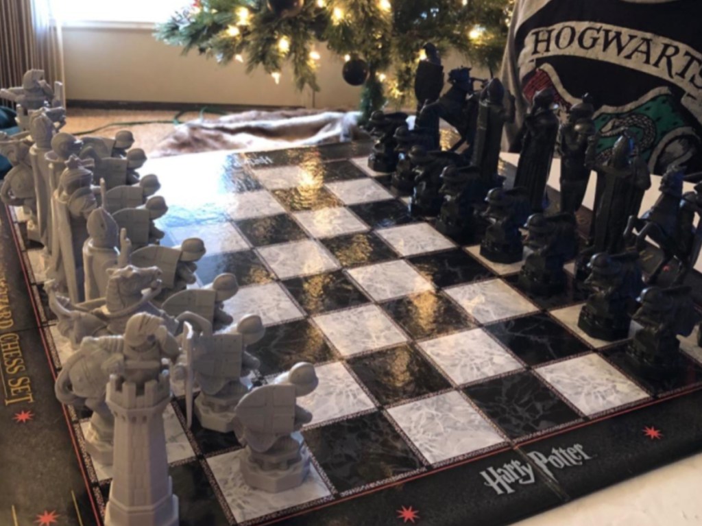 boy sitting behind harry potter chess set all set up and ready to play 