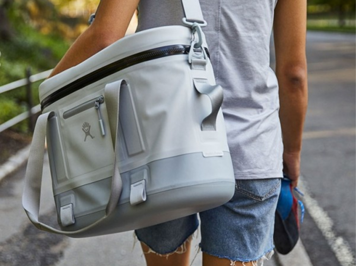 person walking on street carrying gray cooler tote