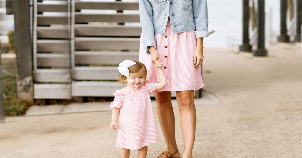 mom with toddler daughter wearing matching pink stripe dresses at beach