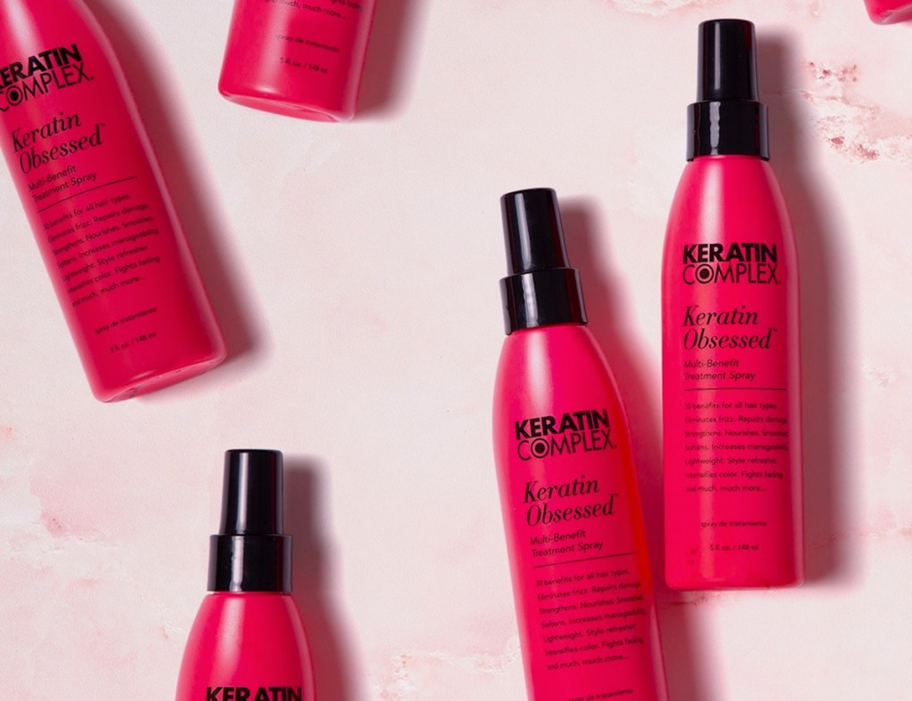 multiple red bottles of Keratin Complex styling spray with black spray caps