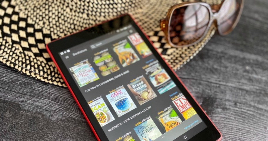 Kindle laying on a hat with books on the kindle