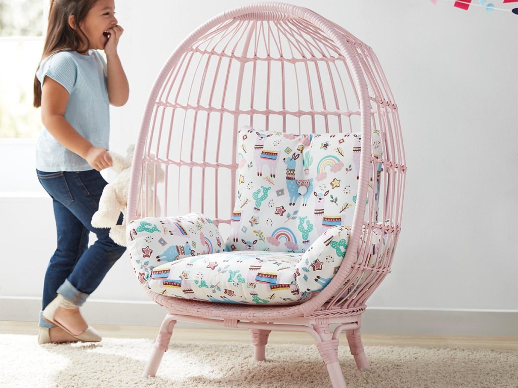 girl walking towards pink egg chair with blue and white patterned cushion