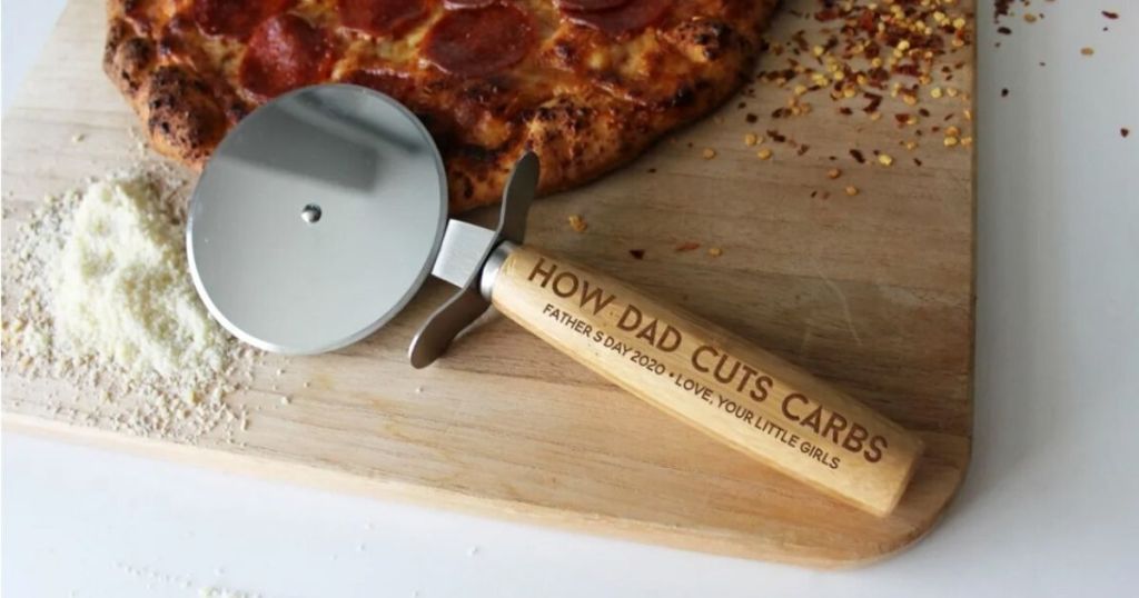 wooden pizza cutter on cutting board with pizza