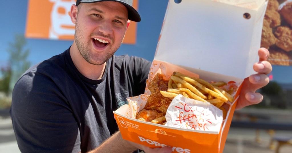 man in front of fast food restaurant holding open box of food