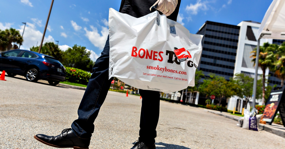 Smokey Bones to go bag in man's hand walking