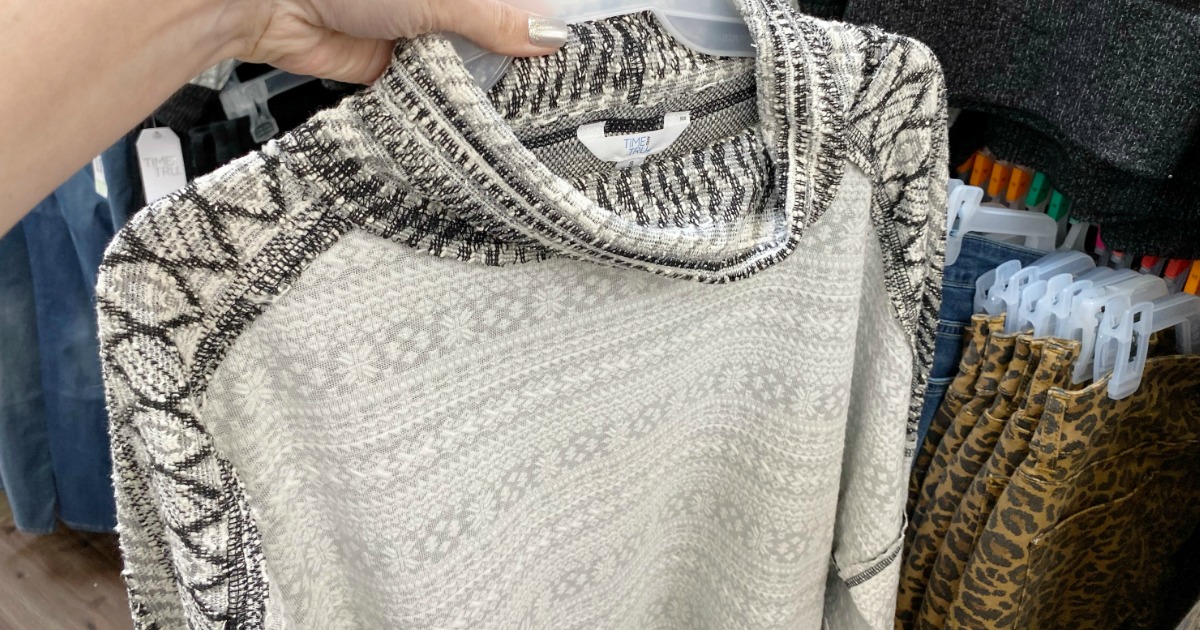 hand holding a sweater on a hanger