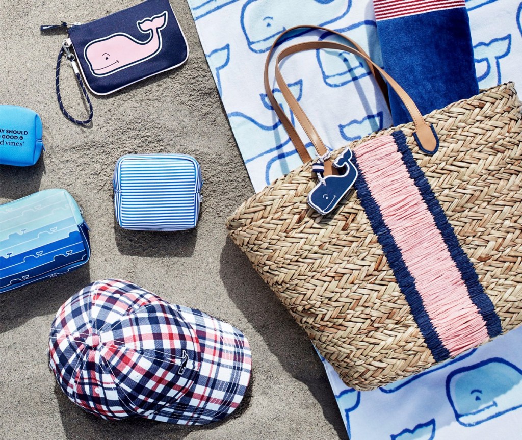beach tote, towel, and accessories printed with vineyard vines whale all sitting on beach sand