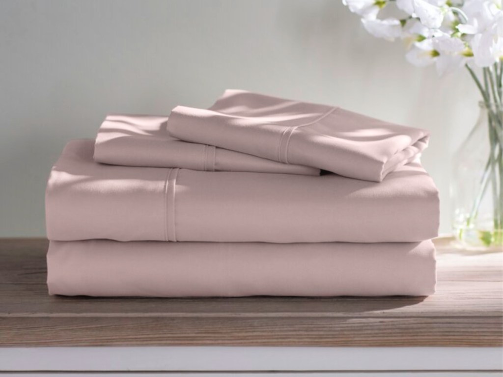 folded blush pink sheets on counter with white flowers in the background