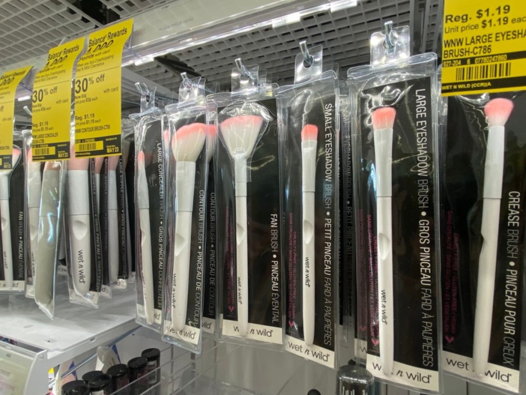 row of white and pink makeup brushes in packaging hanging in store