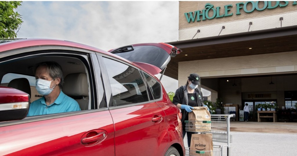High risk man in car w/ face mask picking up groceries at Whole Foods