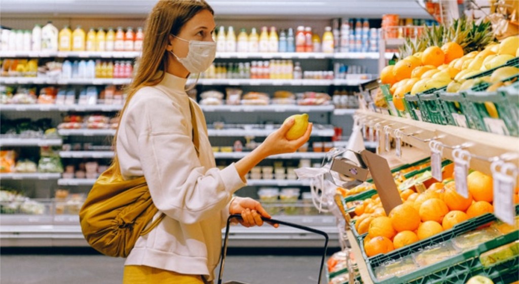 woman in face mask grabbing produce in store