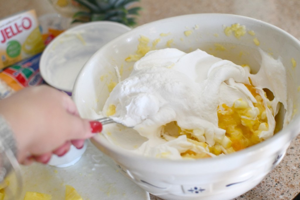 adding whipped topping to pineapple fluff salad