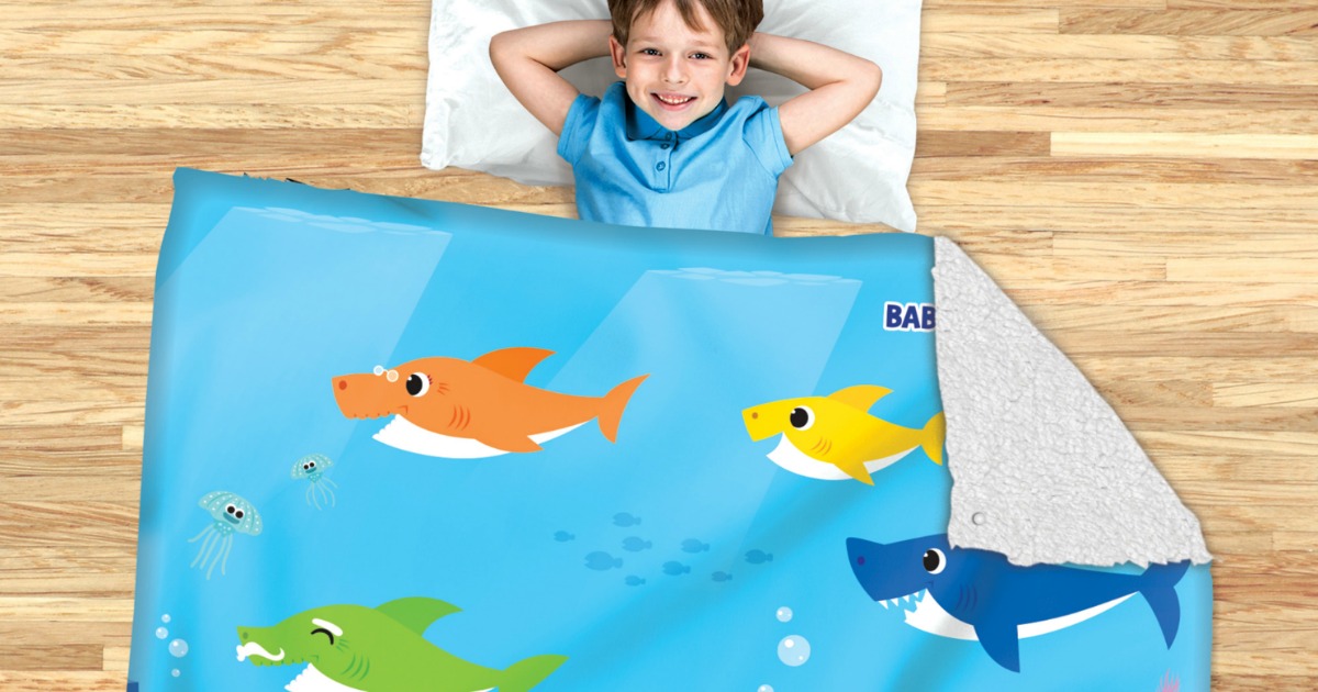 child with head on pillow laying under baby shark blanket