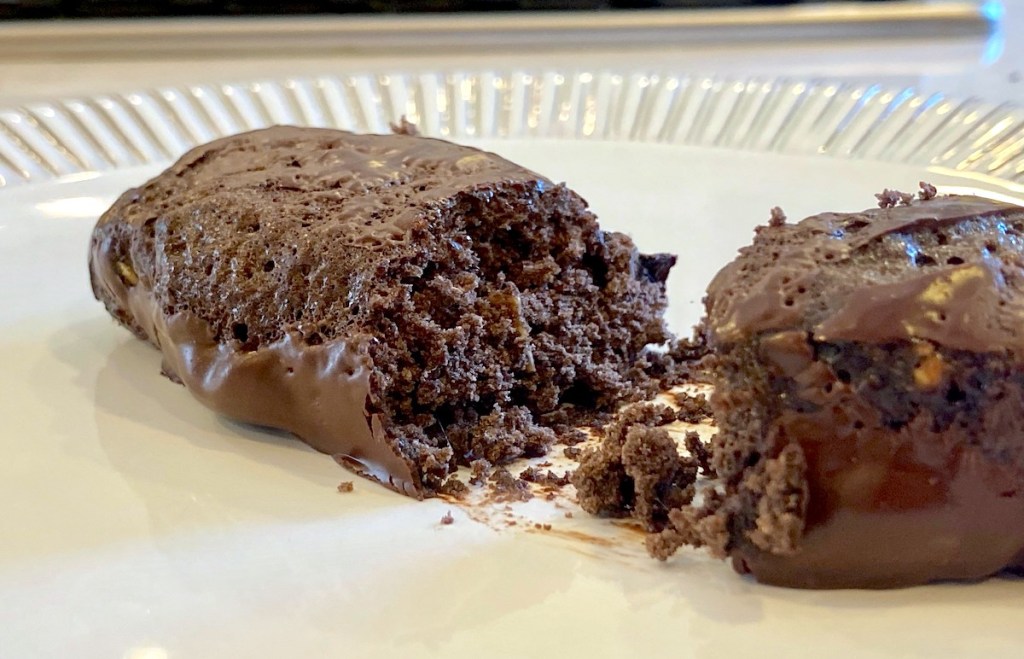 Chocolate protein bar sitting on white plate cut in half