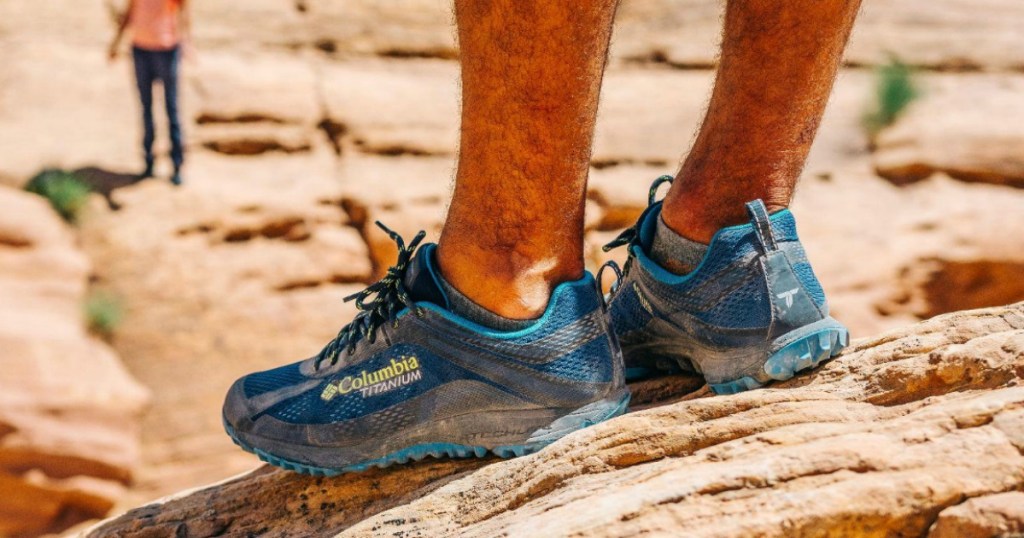 man wearing Columbia shoes on mountain top 