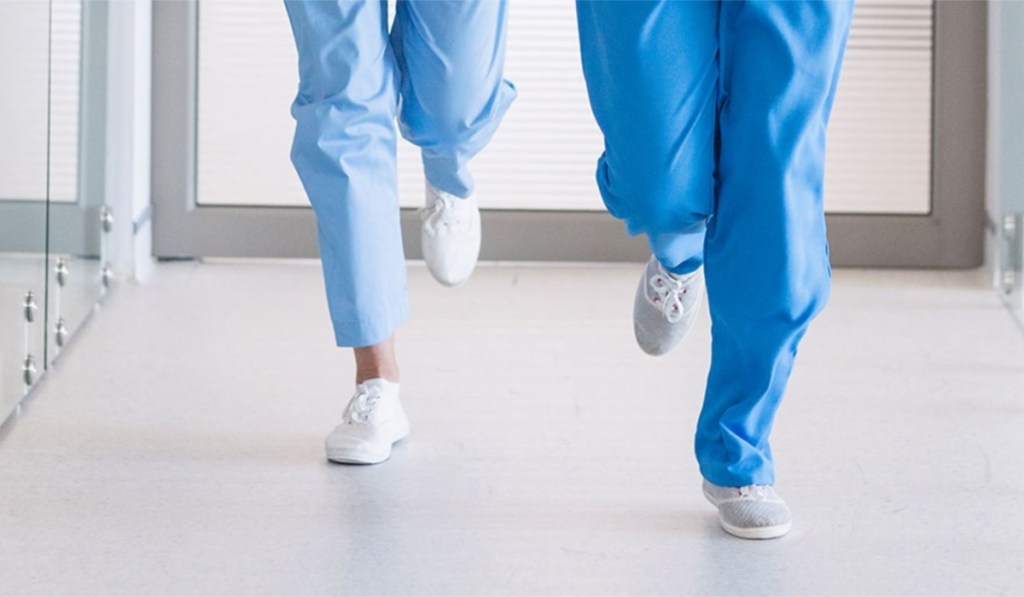 foot level view of medical workers wearing tennis shoes and running