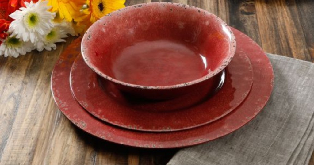 red dinnerware set on table with flower