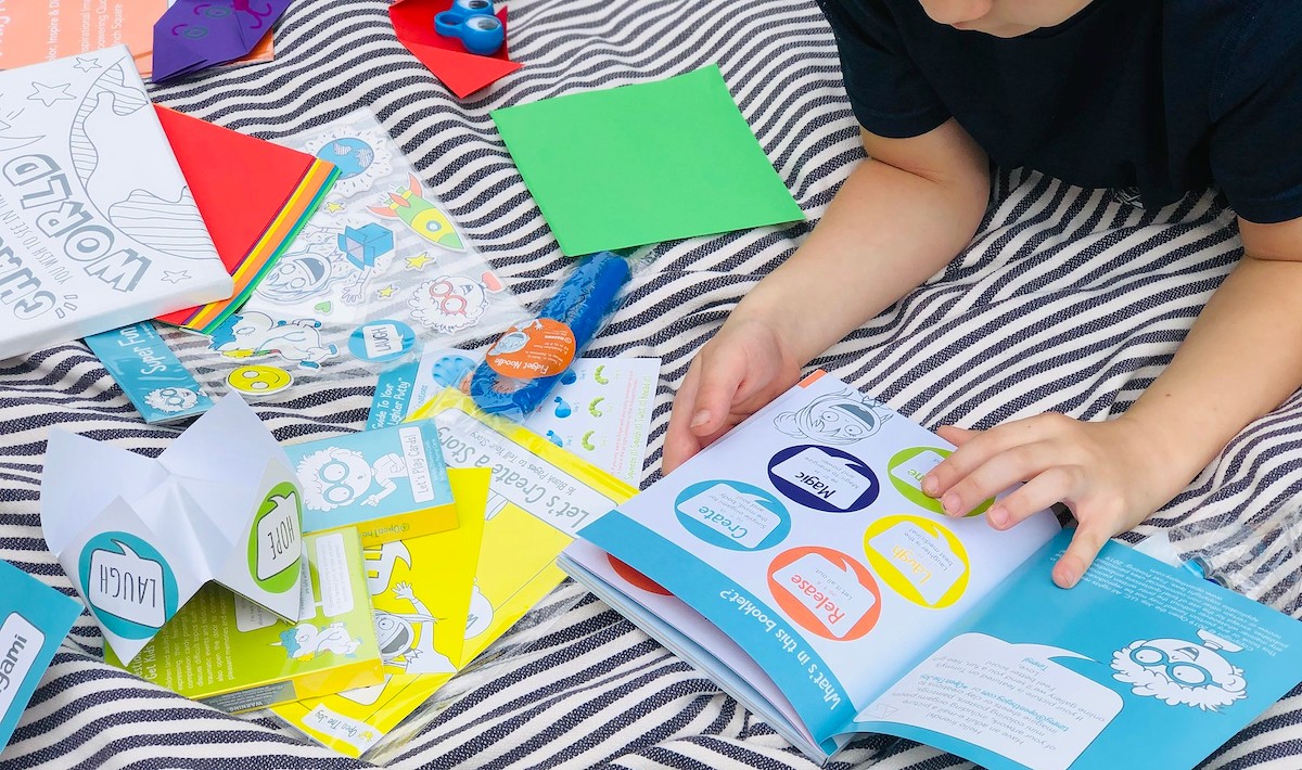 boy reading booklet with other various activities and games on stripe blanket