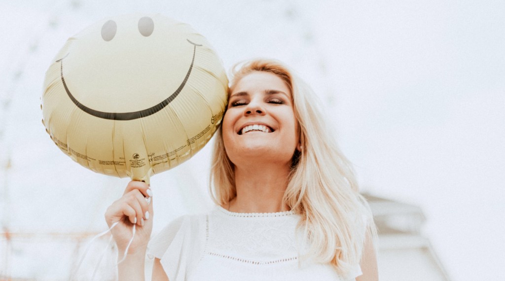 woman holding smiley balloon
