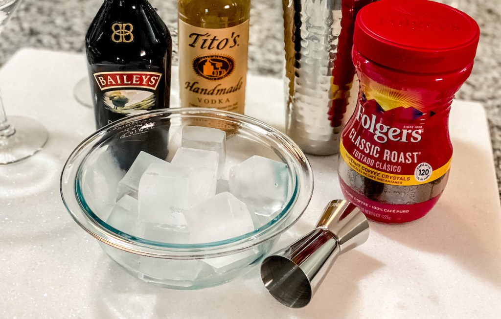 clear bowl of ice cubes with baileys titos and folgers in background