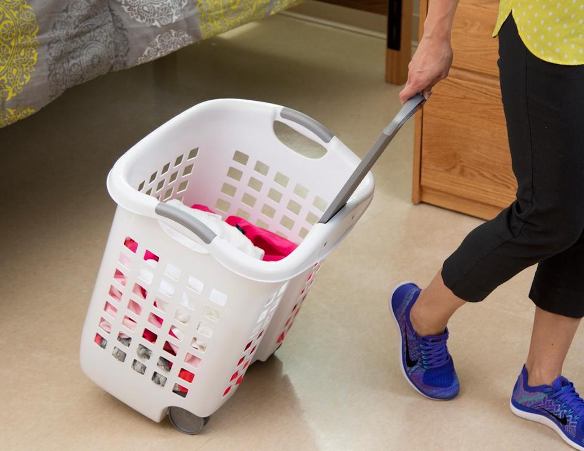 person pulling white laundry basket with wheels